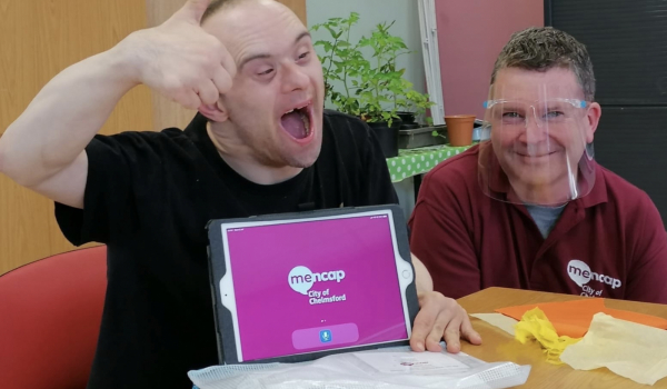 2 people at a computer, with a menace sign on it, one has a learning disability